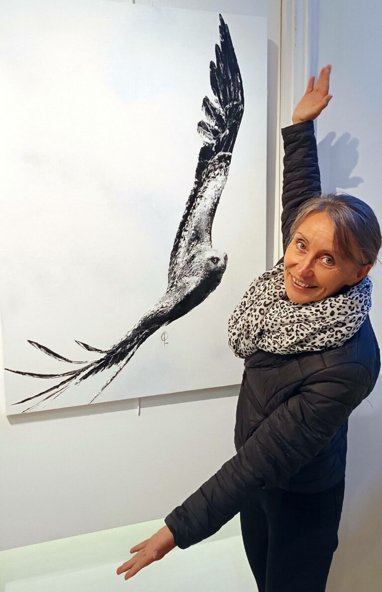 Photo de Soon devant une de ses peinture exposée ; l'aigle noir